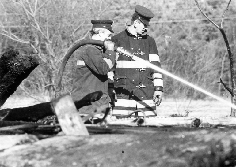 Firefighters Richard O'Neil and Arthur Anderson are putting out a fire c1967